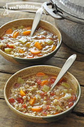 Two bowls are filled with a hearty soup made with vegetables, ground beef and barley.