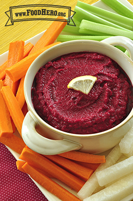 A bowl of beet dip is served with jicama, carrot and celery sticks.