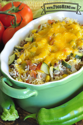 Casserole dish with melted cheese coating a rice and vegetable mix. 