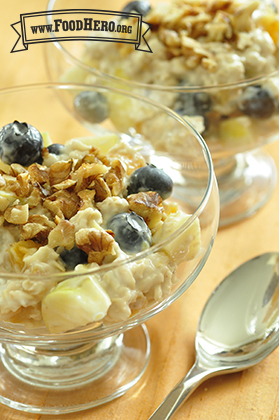 Bowl of oatmeal and yogurt topped with fruit and walnuts. 