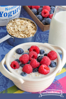 Ceramic bowl with creamy oatmeal topped with raspberries and blueberries.