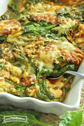 Baking dish with chicken, spinach, sauce and cheese. 