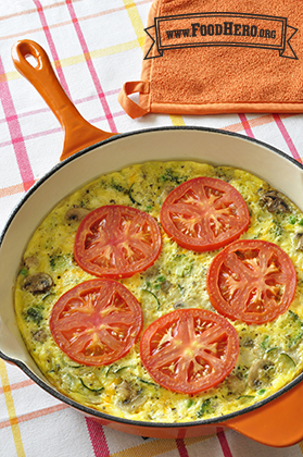 Pan of vegetable and egg mix topped with tomato slices.