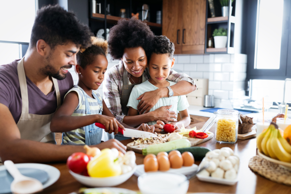 Parents and two children preparing a meal together in the kitchen