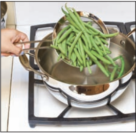 Dumping green beans into boiling water.