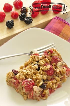 A piece of spiced baked oatmeal with juicy blackberries and raspberries is shown on a plate.