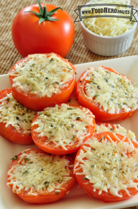 Tomates en rodajas con hierbas y queso asado se muestran en un plato para servir.