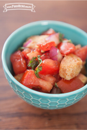 Una sabrosa ensalada de tomates, albahaca y crutones se muestra en un tazón para servir.