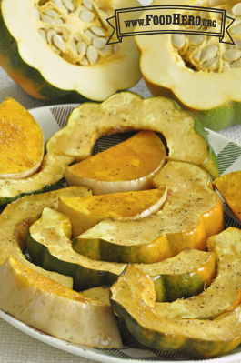Baked crescent shaped acorn squash slices sprinkled with seasoning.