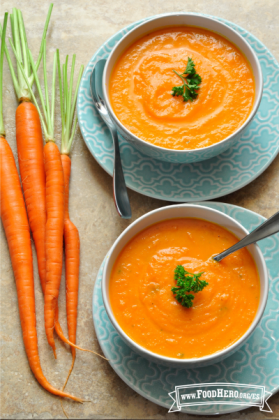 Tazones de sopa de zanahoria suave en platos para servir.
