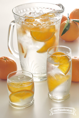 Pitcher of ice water with orange wedges. 