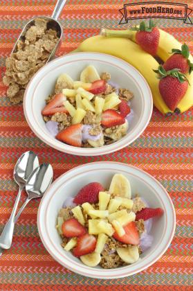 Small bowls of yogurt topped with a cereal and a colorful fruit combination. 