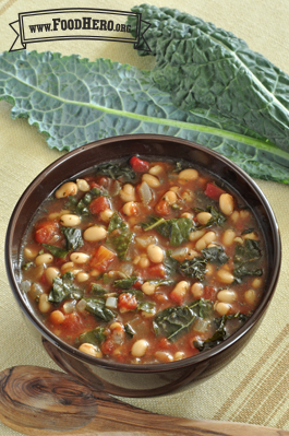 Bowl of soup with a tomato base, kale and beans 