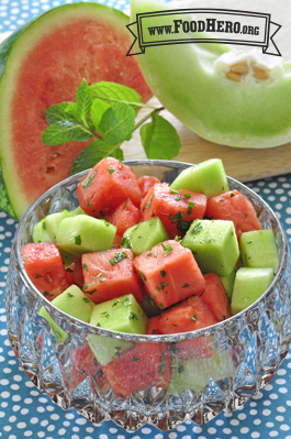 Glass bowl of watermelon and honeydew cubes with mint.