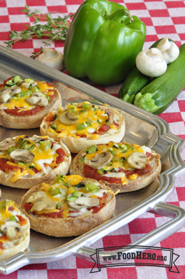 Platter of English muffins with red sauce, vegetables and melted cheese.  