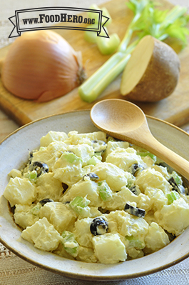 Bowl of potatoes, celery and olives with a creamy dressing.  