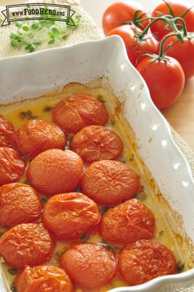 Roasted tomato halves and herbs with a small amount of liquid in the bottom of the baking dish.