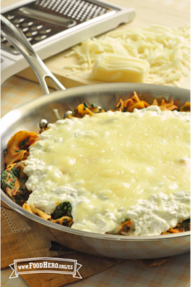 Sartén con fideos, carne y verduras bajo una capa de queso mozzarella derretido.