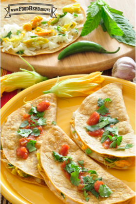 Plato con tortillas de maíz dobladas con queso y rellenas de flor de calabaza con salsa.