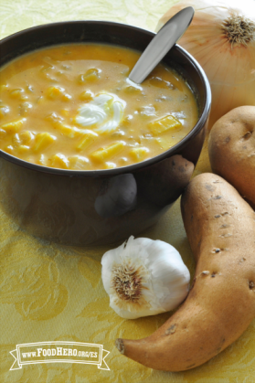 Tazón con sopa cremosa anaranjada con una cucharada de crema agria.