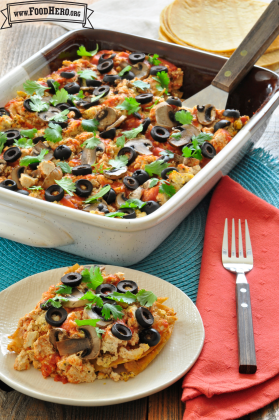 Casserole dish with a tofu and vegetable mix topped with black olives and cilantro.