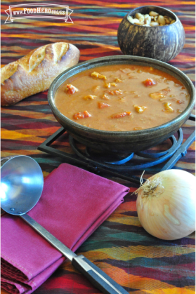 Tazón con sopa cremosa de tomate y cacahuate con verduras y pollo.