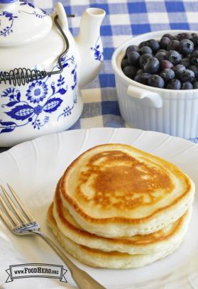Stack of golden pancakes with a side of blueberries.