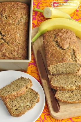 A loaf of Banana Oatmeal Bread is sliced to show a golden brown top and moist inside texture.