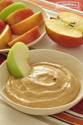 Small bowl of yogurt and peanut butter mix served with sliced apples.