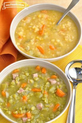 Two bowls of green and yellow pea and vegetable soup.