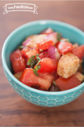 Flavorful salad of tomatoes, basil and croutons is shown in a serving bowl.