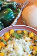 Bowl of seasoned butternut squash topped with shredded cheese.