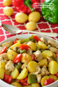 Tazón lleno con papas al horno del tamaño de un bocado, pollo y pimientos dulces.