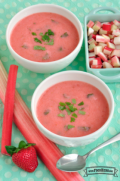 Two bowls of Strawberry Rhubarb Soup displayed with fresh strawberries and rhubarb