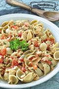 Bowl of pasta shells and salmon garnished with parsley.
