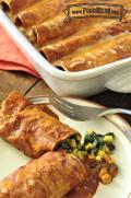 Casserole dish with tortillas filled with a bean, corn and spinach mix with red sauce.