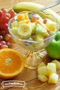 Footed glass dish with a creamy fruit salad.