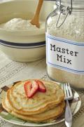 Plate of fluffy pancakes shown with a mixing bowl filled with the Master Mix.