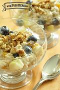 Bowl of oatmeal and yogurt topped with fruit and walnuts.