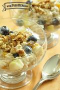 Bowl of oatmeal and yogurt topped with fruit and walnuts. 