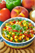 Tazón pequeño de una colorida salsa de durazno y verduras exhibida con galletas saladas.