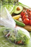 Plastic bag holding salad and dressing.