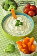 Bowl of creamy dip garnished with parsley and served with raw carrots, cherry tomatoes and broccoli. 