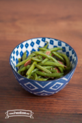 Bowl of green beans with ham and onions.