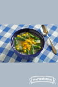 Bowl of soup with asparagus and potatoes topped with cheddar cheese.