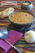 Bowl of creamy soup with a tomato and peanut base with vegetables and chicken.