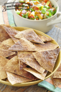 Tortilla chips sprinkled with cinnamon are displayed on a platter with a bowl of peach salsa for dipping.
