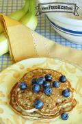 Two golden brown banana pancakes are topped with fresh blueberries.