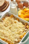 Baking dish with a layer of bread cubes, peaches and a crumbly topping.