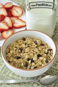 Bowl of rolled oats and raisins served with milk and strawberries.